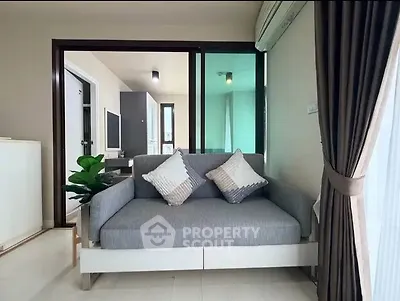 Modern living room with stylish sofa and large window, offering a cozy and inviting atmosphere.