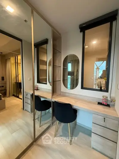 Modern bedroom with stylish vanity and elegant chair, featuring ample storage and natural light.