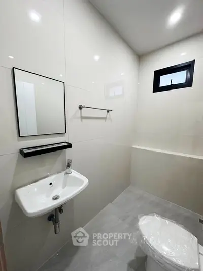 Modern minimalist bathroom with sleek white tiles and compact fixtures.