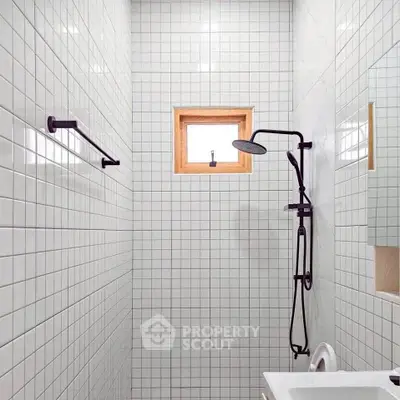 Modern minimalist bathroom with sleek black fixtures and white tiled walls.