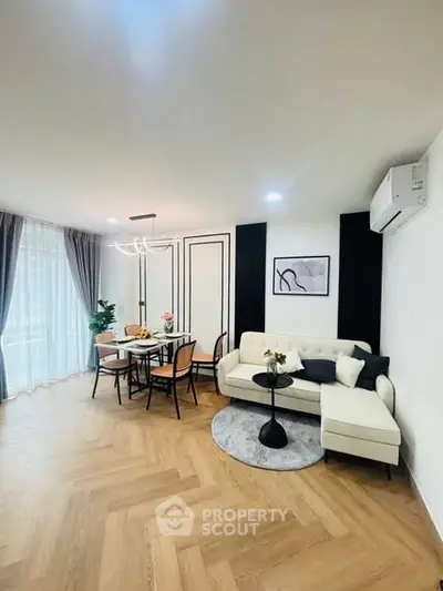 Elegant living room with modern furniture and dining area, featuring stylish decor and natural light.