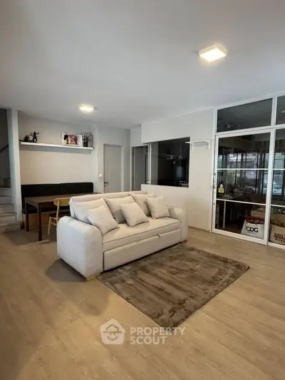 Spacious modern living room with cozy sofa and dining area, perfect for relaxation and entertaining.