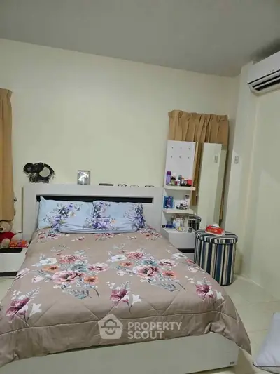 Cozy bedroom with floral bedding and air conditioning, perfect for restful nights.