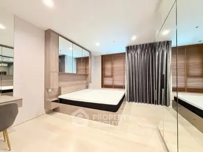 Modern bedroom with sleek design, mirrored wardrobe, and elegant window treatments in a stylish apartment.