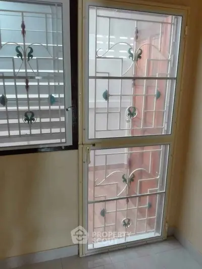 Secure window with decorative iron grill in a well-lit room, offering safety and style for modern homes.