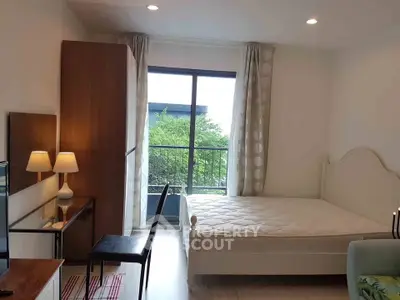 Cozy bedroom with natural light and balcony view, featuring a stylish bed and modern decor.