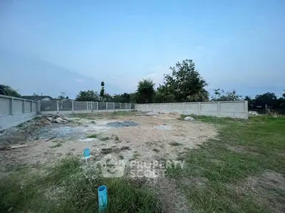 Spacious vacant land plot with boundary walls, ideal for development in a serene neighborhood.