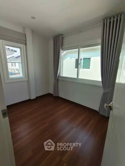 Bright empty room with wooden flooring and large windows in modern home