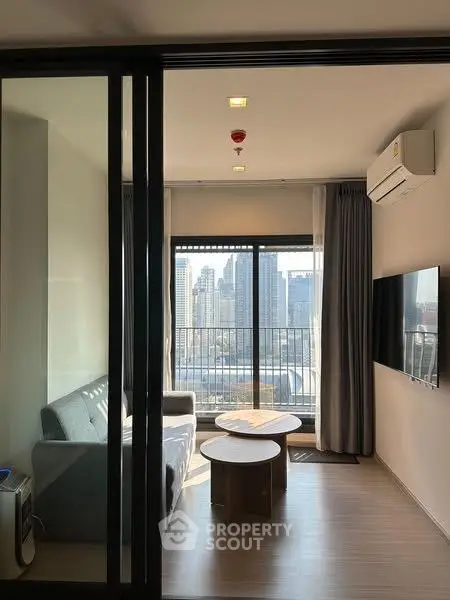 Modern living room with city view, featuring sleek furniture and large windows for natural light.