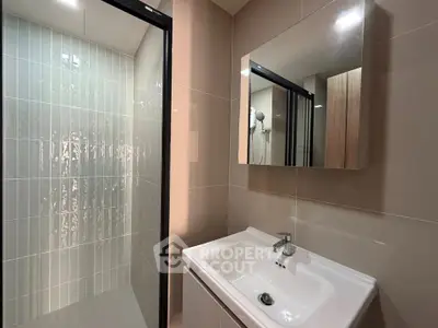 Modern bathroom with sleek sink and glass shower enclosure in contemporary apartment.