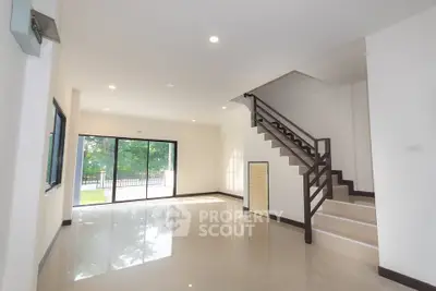 Spacious modern living room with large windows and staircase, offering abundant natural light.