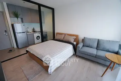 Modern studio apartment with cozy bed, compact kitchen, and stylish sofa.