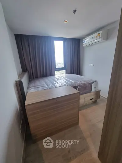 Cozy bedroom with twin beds and large window offering natural light and city views.