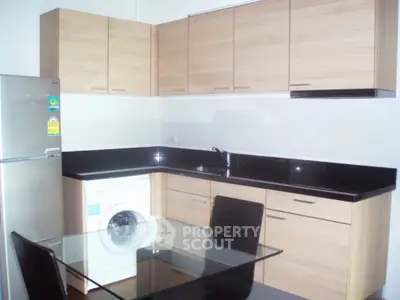 Modern kitchen with sleek cabinets, glass dining table, and built-in washing machine.