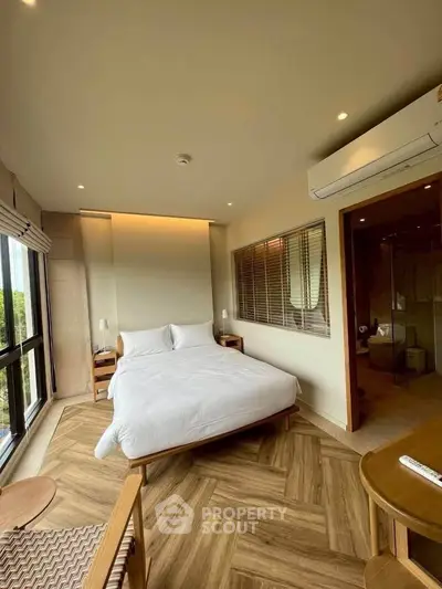 Modern bedroom with large windows, wooden flooring, and stylish decor in a luxurious apartment.
