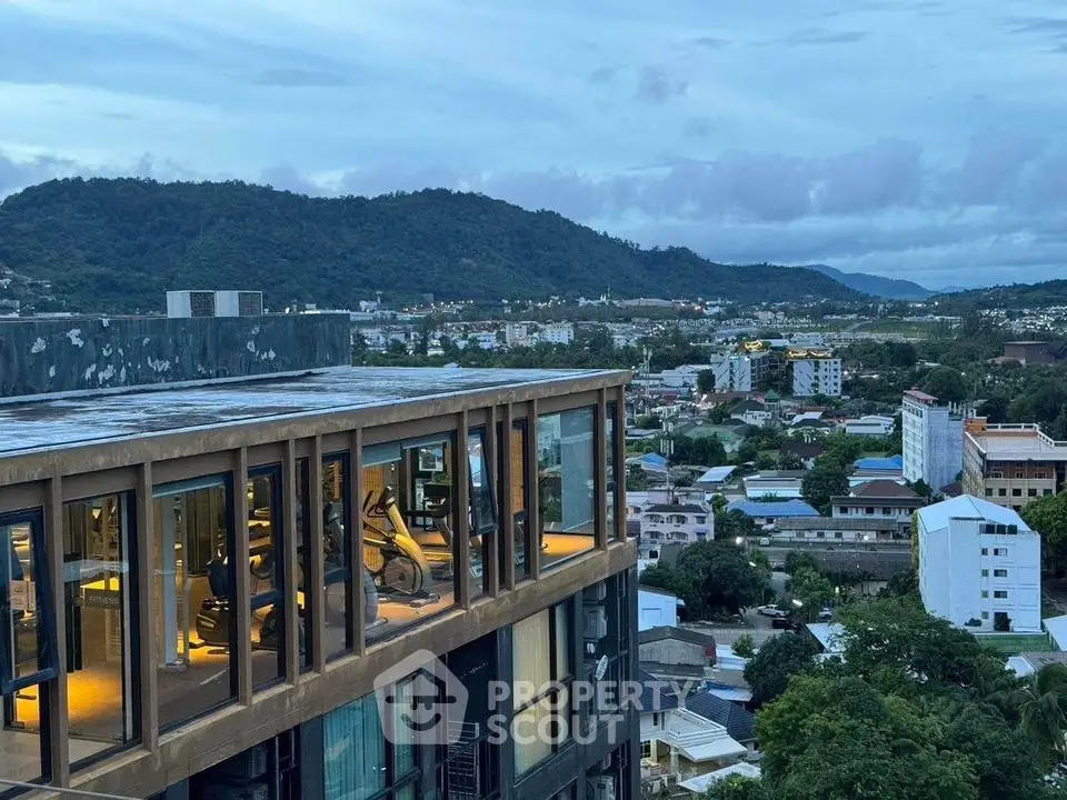 Stunning rooftop view from modern building overlooking cityscape and mountains.