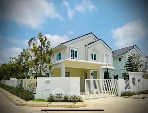 Charming suburban house with white facade and spacious driveway under clear blue sky.