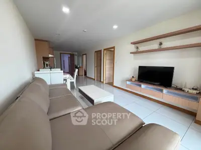 Spacious modern living room with sleek furniture and wall-mounted TV, perfect for relaxation.