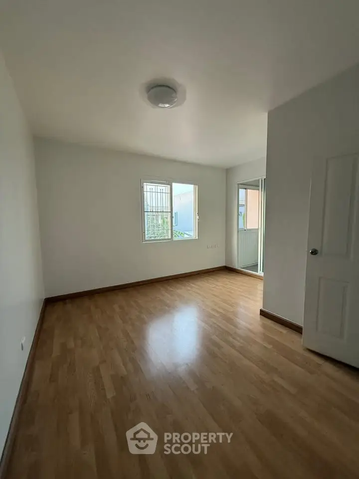 Spacious empty room with wooden flooring and natural light, perfect for customization.