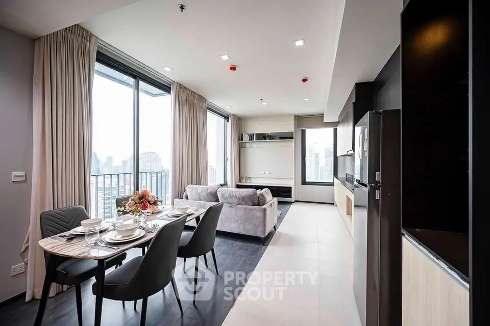 Modern open-layout living and dining area with city view, featuring elegant furniture and large windows.
