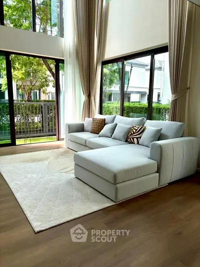 Spacious living room with large windows and modern sofa, offering a bright and inviting atmosphere.