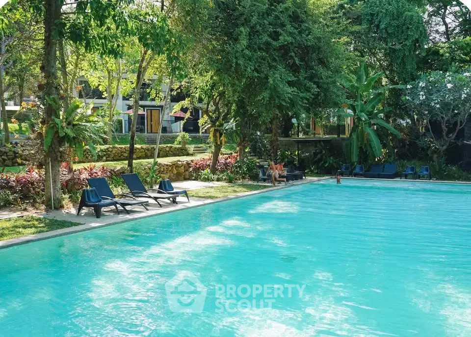 Luxurious outdoor pool surrounded by lush greenery in a serene setting.
