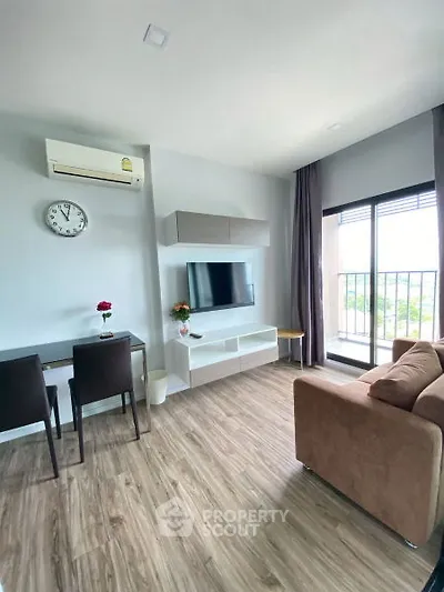 Modern living room with balcony, featuring sleek furniture and natural light.