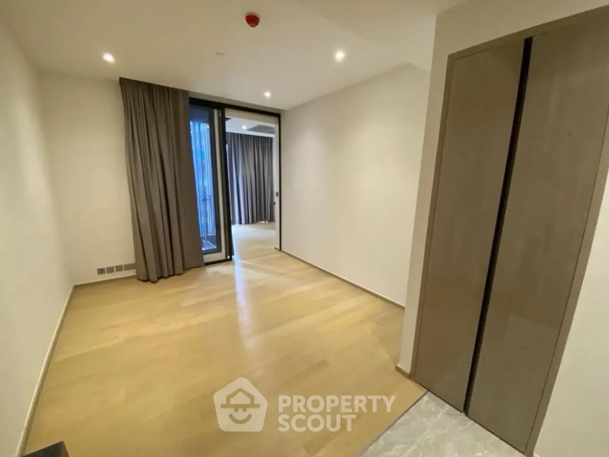 Spacious modern apartment interior with wooden flooring and large windows.