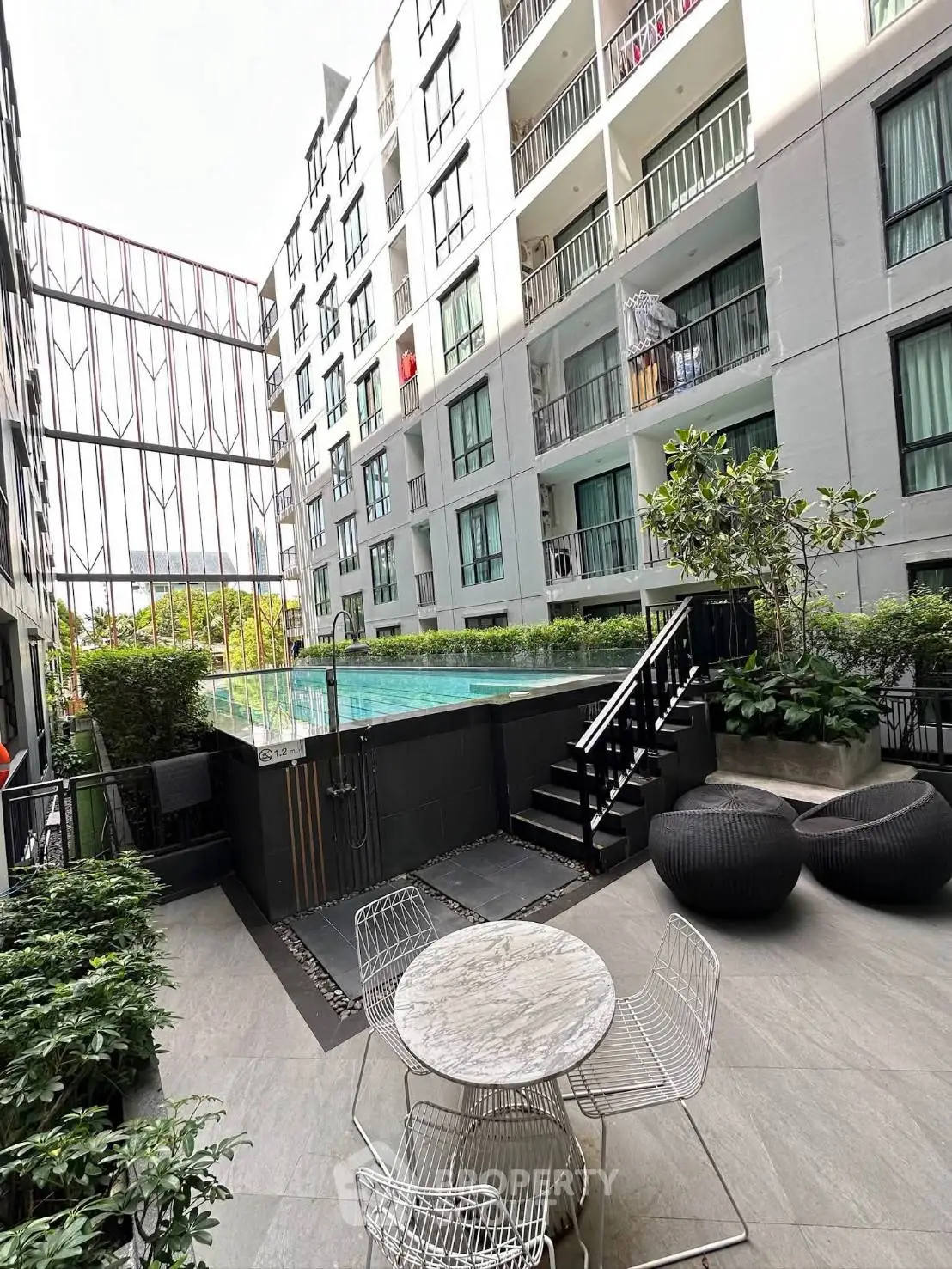 Modern apartment building with pool and stylish outdoor seating area, perfect for relaxation and leisure.