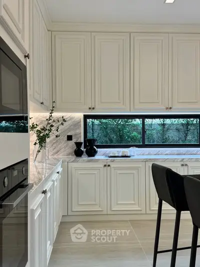 Elegant kitchen with white cabinetry and modern appliances, featuring a sleek open layout and stylish decor.