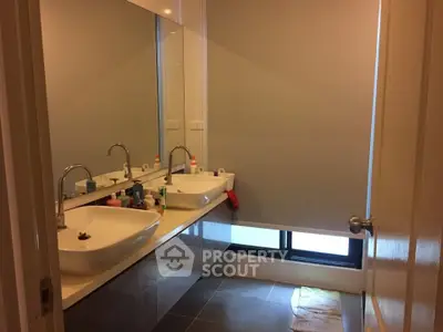 Modern bathroom with dual sinks and large mirror in a stylish home.