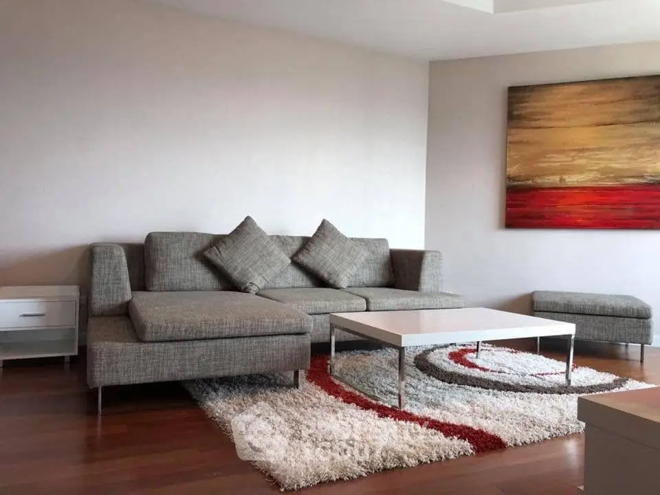 Modern living room with stylish gray sofa, abstract art, and cozy rug on wooden floor.