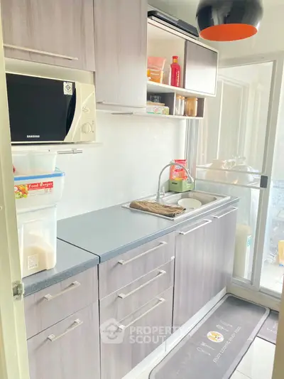 Modern kitchen with sleek cabinetry and sliding glass door access to balcony.