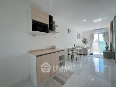 Modern open-plan living room with sleek kitchen and bright balcony view
