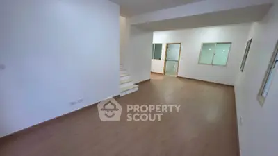 Spacious open-plan living area with wooden flooring and staircase
