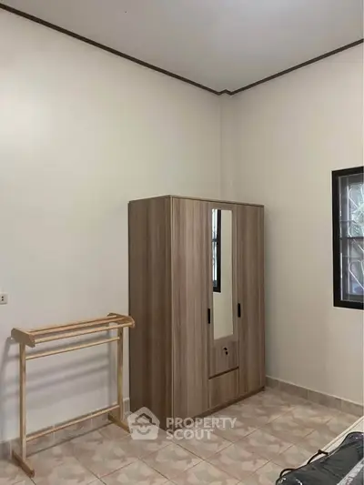 Cozy bedroom with wooden wardrobe and clothes rack, perfect for organizing your space.