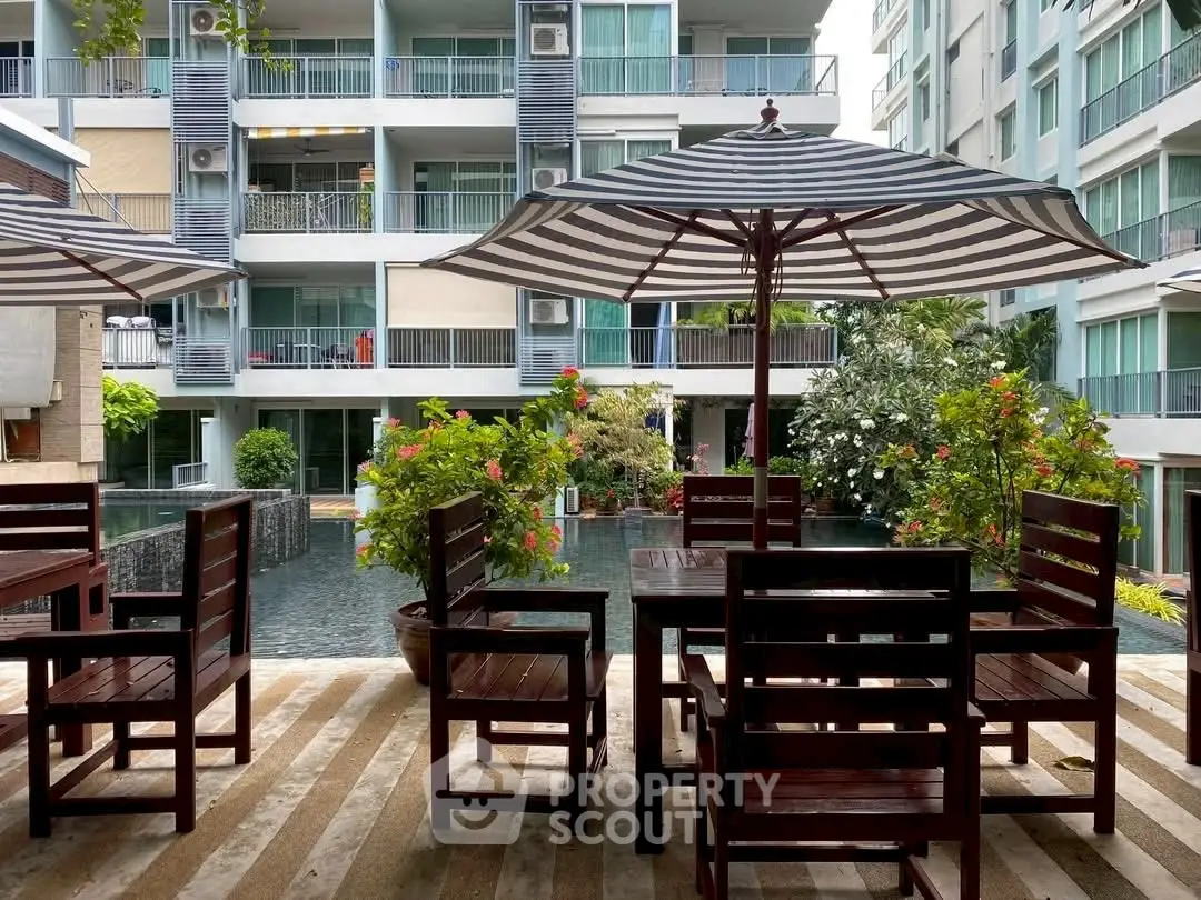 Modern apartment complex with poolside seating and lush greenery