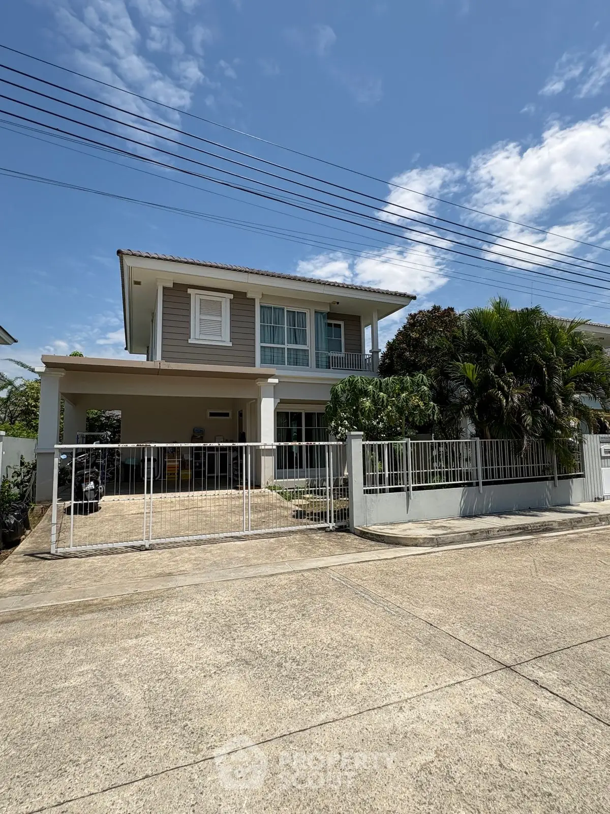 Charming two-story house with lush garden and gated entrance in a serene neighborhood.