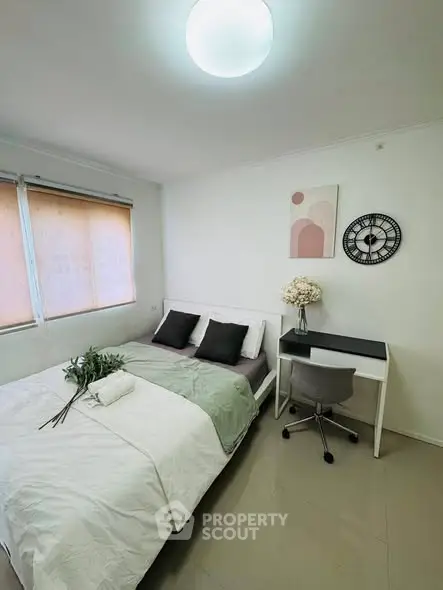 Cozy bedroom with modern decor, featuring a comfortable bed, desk, and stylish wall clock.