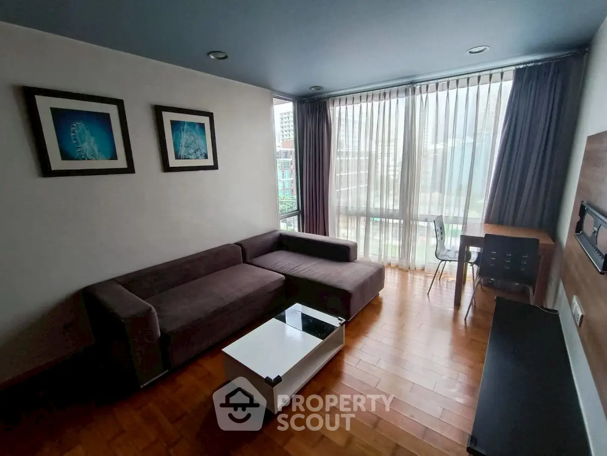 Modern living room with large windows and stylish furniture in a city apartment.