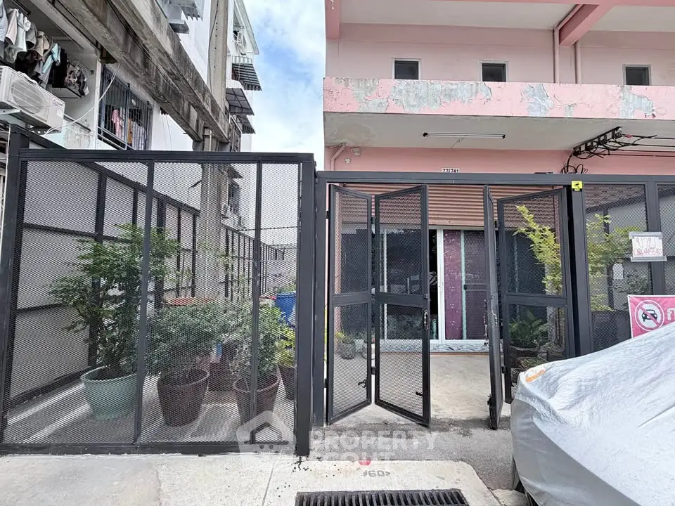 Charming urban property with gated entrance and potted plants, offering privacy and security in a vibrant neighborhood.
