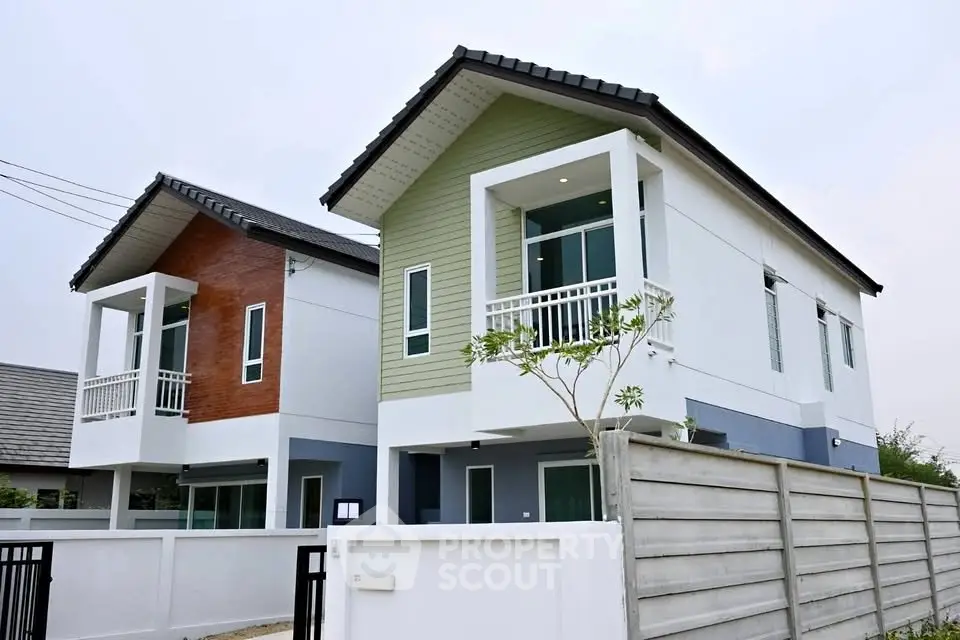 Modern two-story houses with stylish facades and small balconies in a suburban neighborhood.