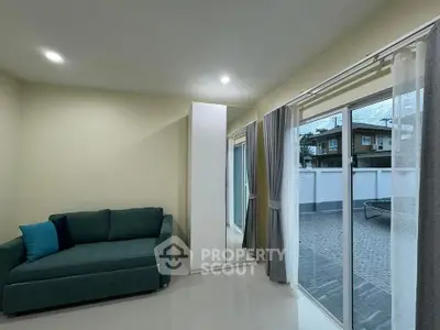 Modern living room with large windows and cozy sofa overlooking patio
