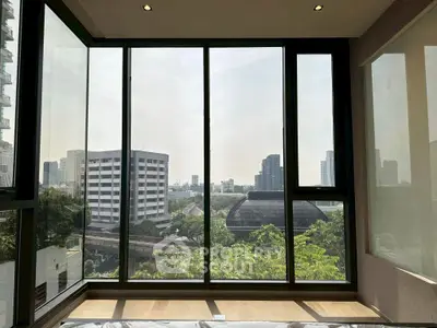 Spacious room with floor-to-ceiling windows offering stunning cityscape views.