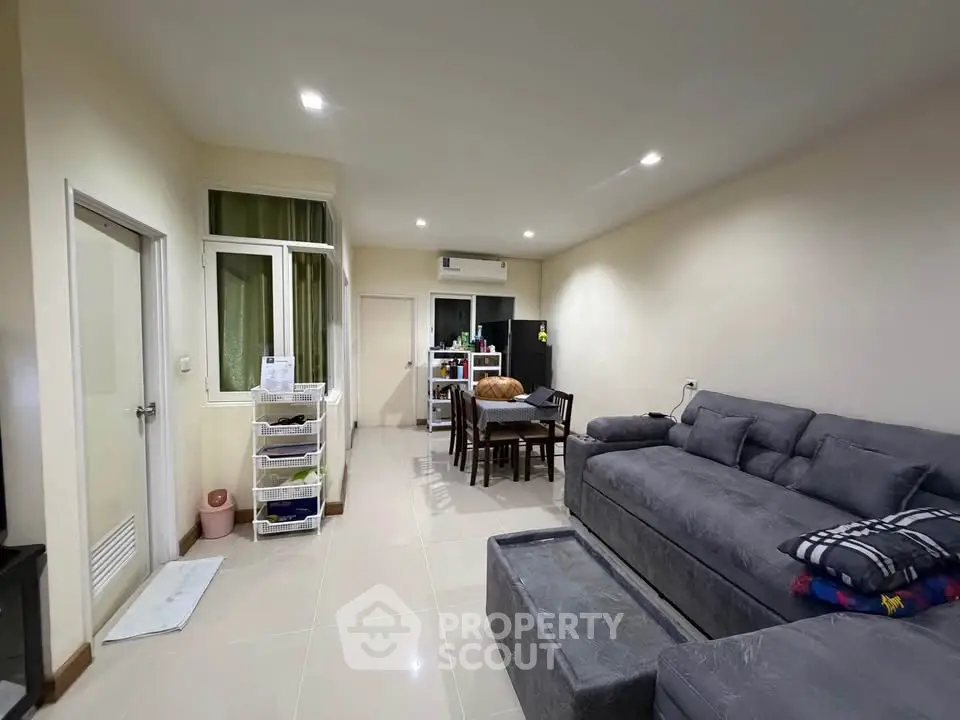 Spacious living room with modern furniture and dining area in a cozy apartment.