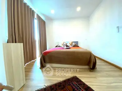 Spacious bedroom with modern decor and large window for natural light.