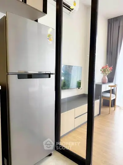 Modern apartment interior with sleek kitchen and stylish living area, featuring a stainless steel fridge and elegant decor.