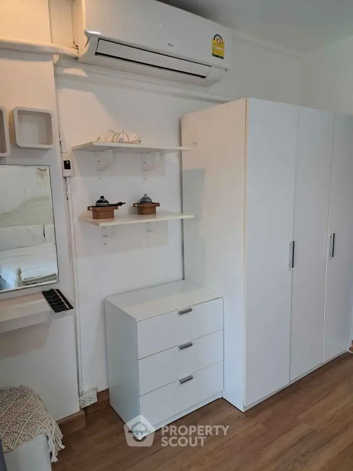 Modern bedroom with sleek white furniture and air conditioning unit, perfect for comfort and style.