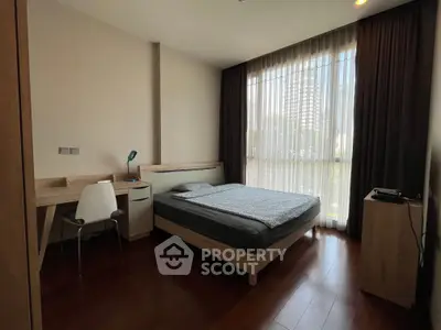 Modern bedroom with large window and wooden flooring in a stylish apartment.