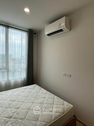 Cozy bedroom with air conditioning and large window offering natural light.